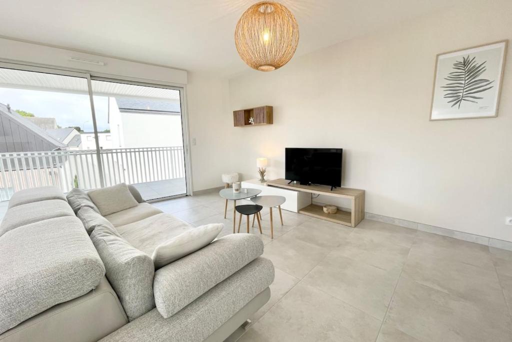 a white living room with a couch and a table at Spacieux appartement neuf de standing Hyper Cosy in Larmor-Plage