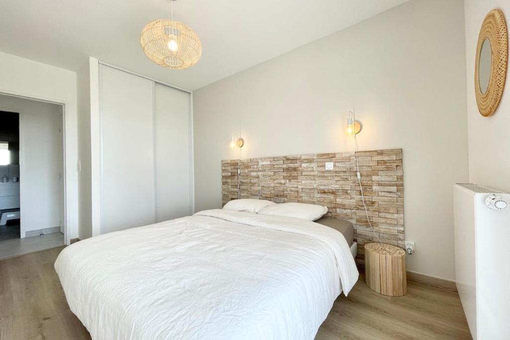 a bedroom with a large white bed and a brick wall at Spacieux appartement neuf de standing Hyper Cosy in Larmor-Plage