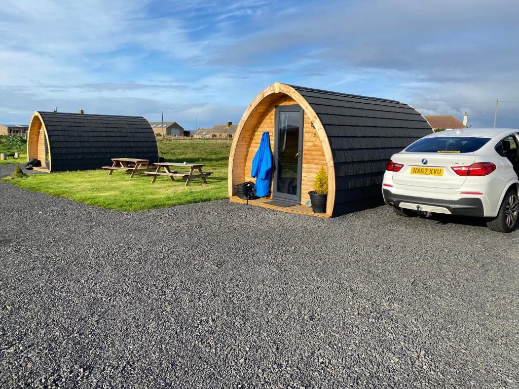 een auto geparkeerd voor een kleine tent bij North Point Pods (north coast 500) in Thurso