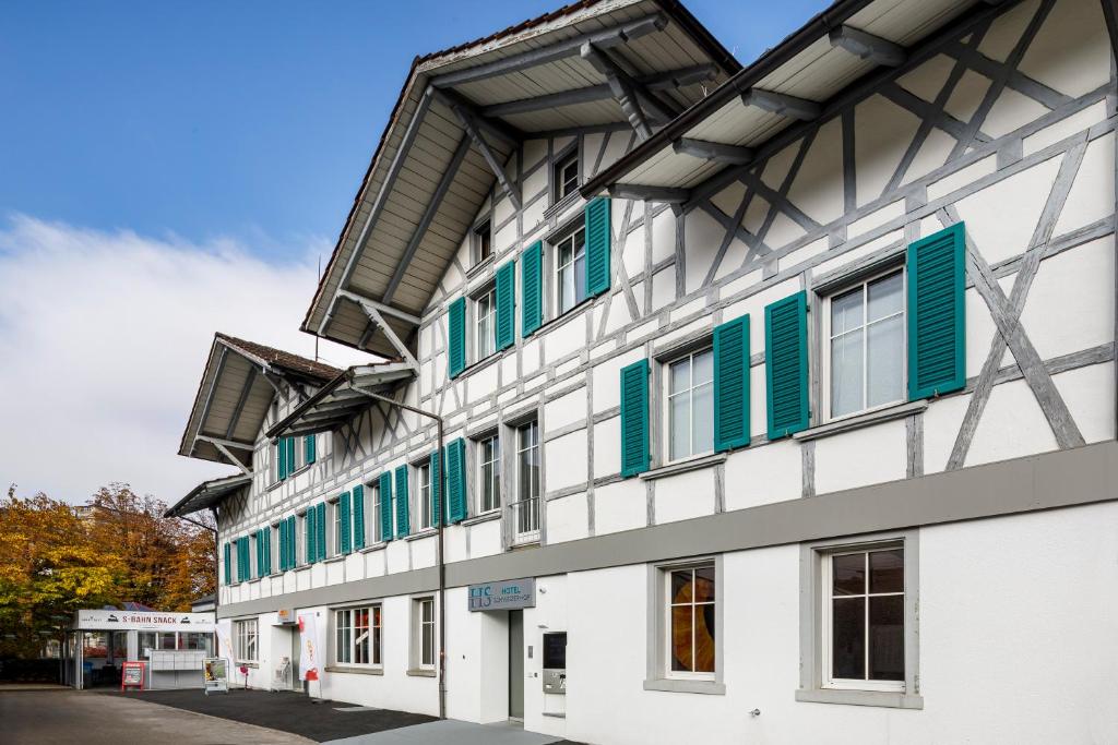 a white building with green shutters on it at Hotel Schweizerhof in Wetzikon