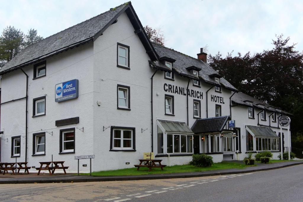 a white building with picnic tables in front of it at BEST WESTERN The Crianlarich Hotel in Crianlarich