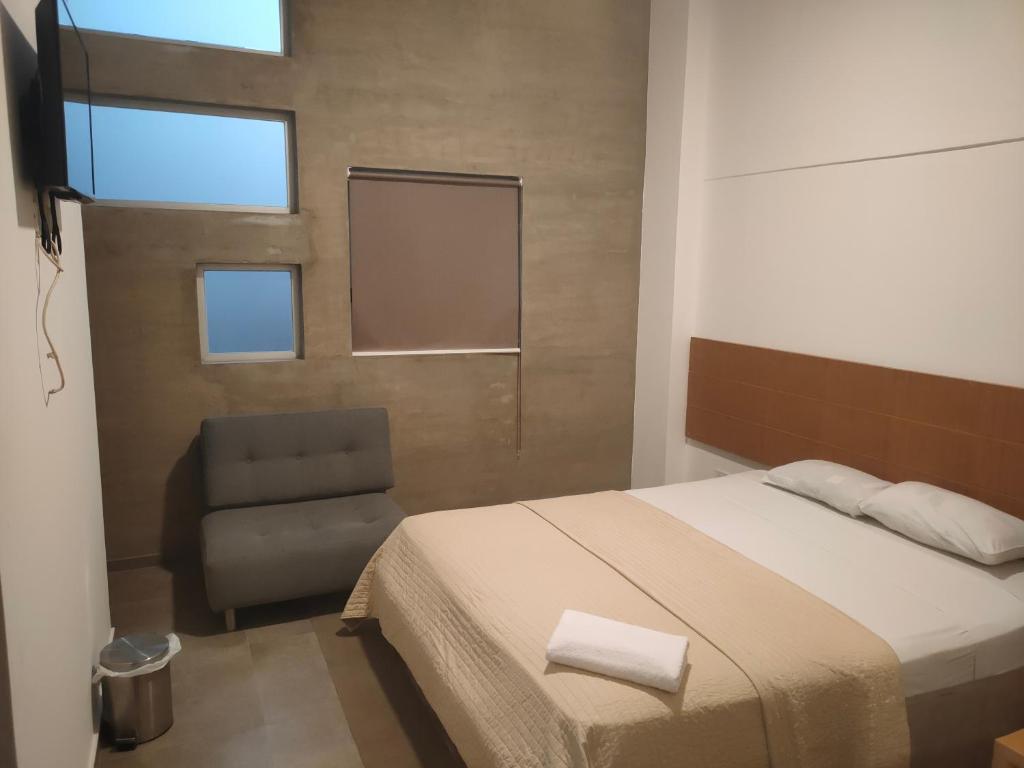 a bedroom with a bed and a chair at HOTEL BOUTIQUE PANAMÁ in Guayaquil