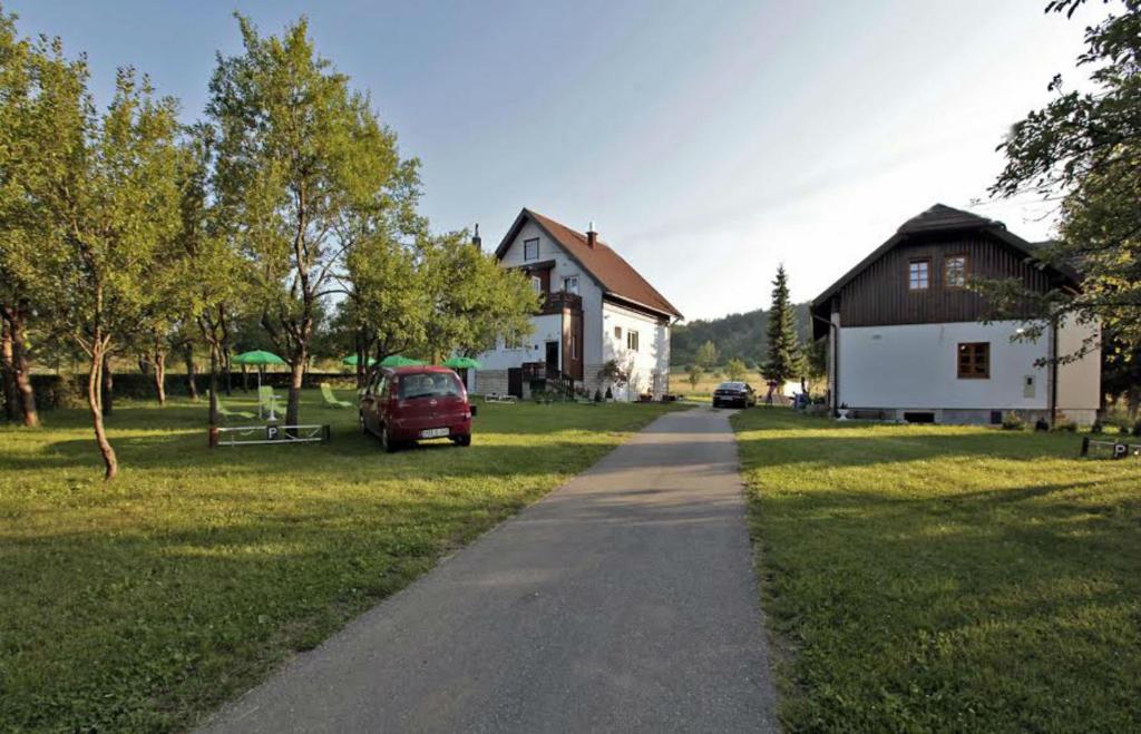 a road in a field with a house and a car at Adriana Guesthouse in Jezerce