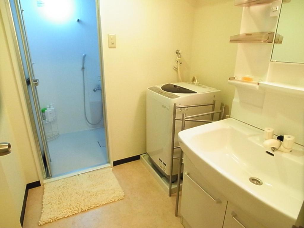 uma pequena casa de banho com um lavatório e um frigorífico em Asayake em Tóquio