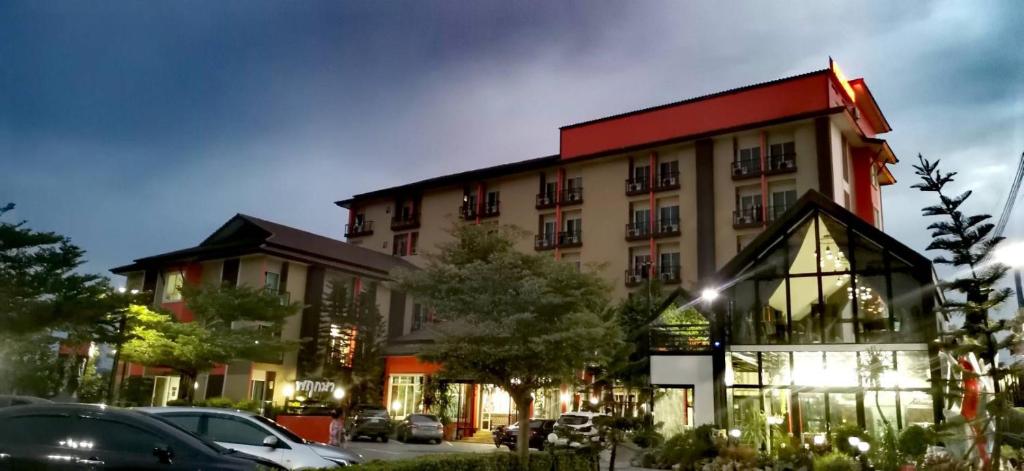 a large building with cars parked in a parking lot at Grand Pruksa Siri Apartment in Sara Buri