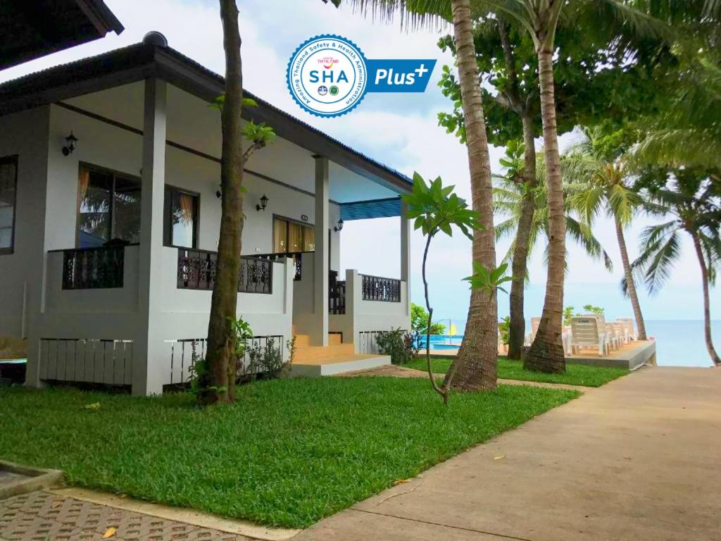 a building with palm trees in front of the ocean at Marina Beach Resort - SHA Extra Plus in Lamai