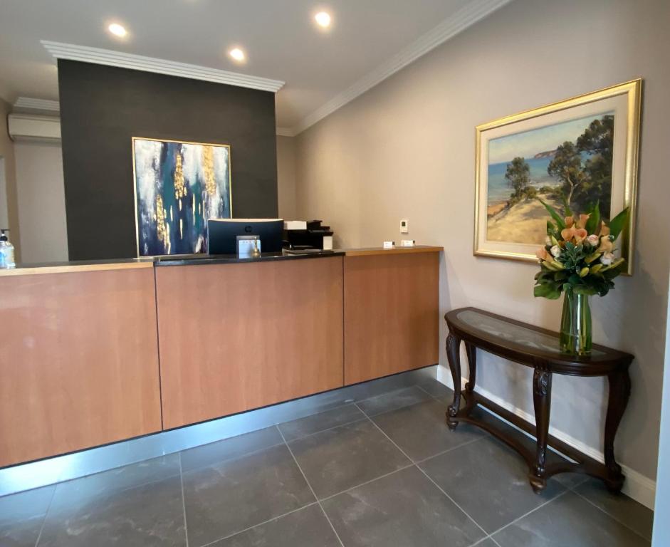 a reception desk with a vase of flowers on a table at Sunseeker Motor Inn in Batemans Bay