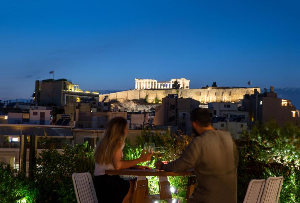 Ein Mann und eine Frau sitzen an einem Tisch mit Weingläsern. in der Unterkunft B4B Athens Signature Hotel in Athen