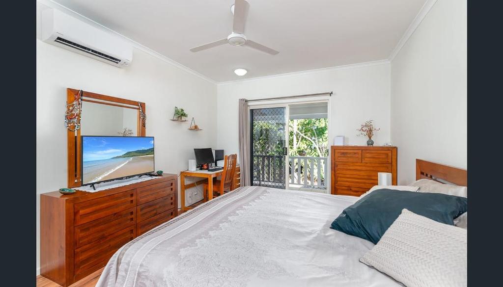 1 dormitorio con 1 cama, TV y ventana en Modern 2 bedroom townhouse - Four Mile Beach Escapes, en Port Douglas
