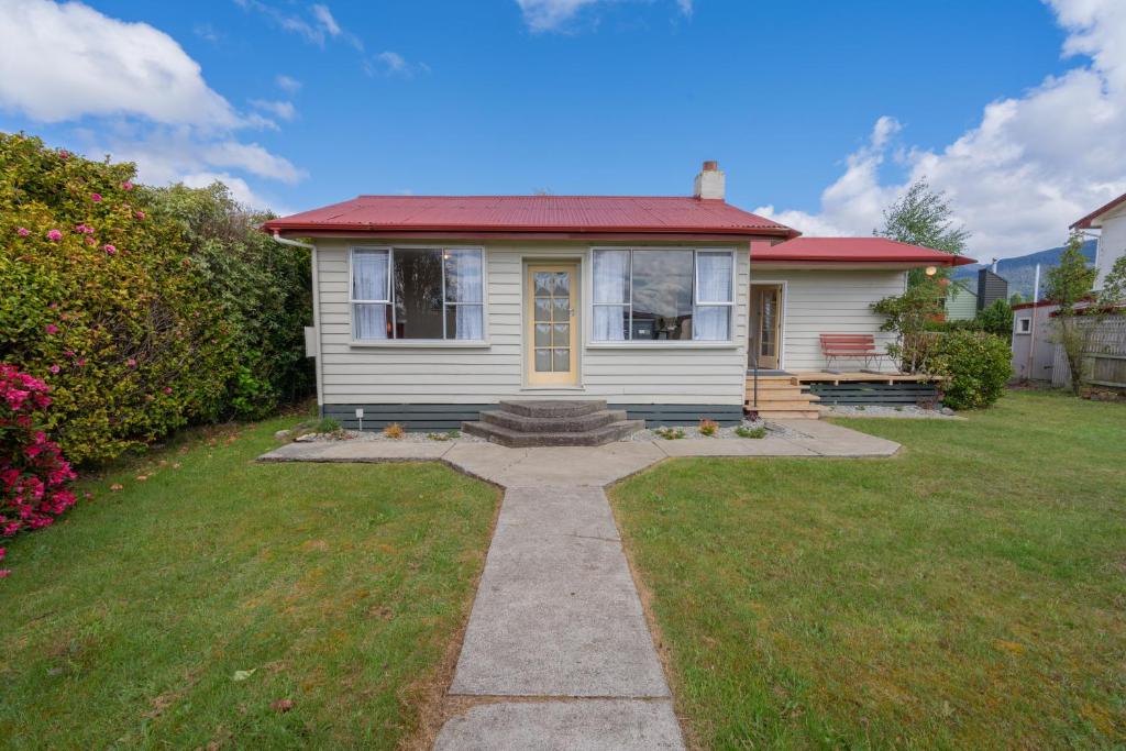 蒂阿瑙的住宿－Rustlein Cottage - Te Anau Holiday Home，一间白色的小房子,有红色的屋顶
