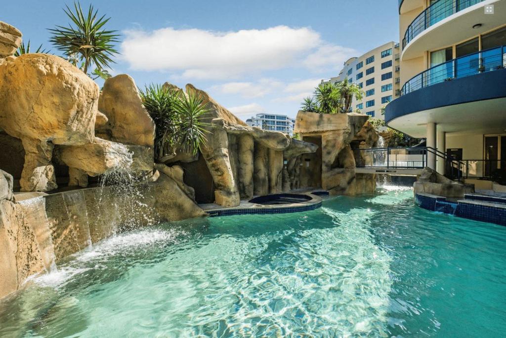 a swimming pool with a waterfall in a resort at Mooloolaba Beachfront: Superior Resort Apartment in Mooloolaba