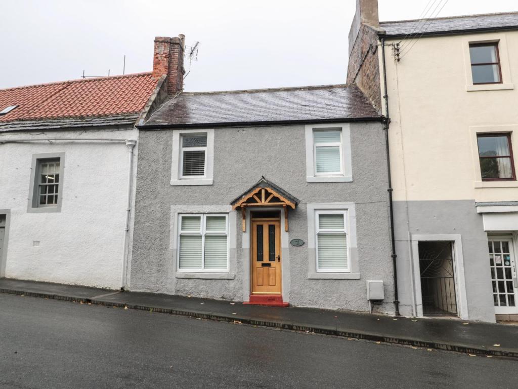 a house with a red door on a street at Church View Cottage in Wooler