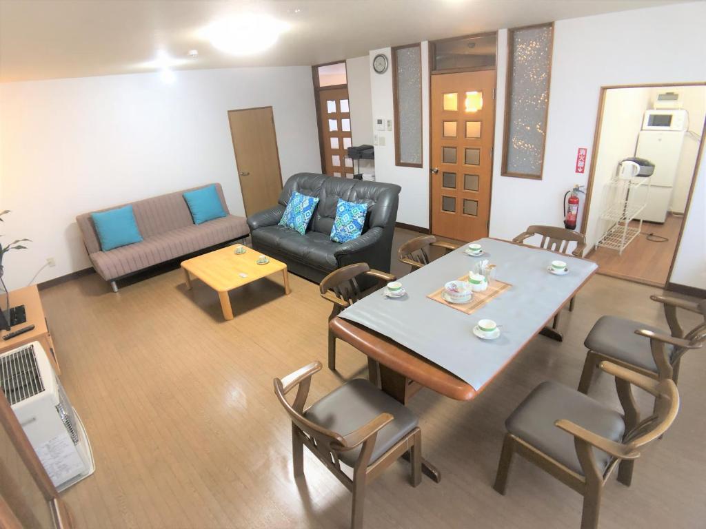 ein Wohnzimmer mit einem Tisch, Stühlen und einem Sofa in der Unterkunft STAY3‐11 in Asahikawa