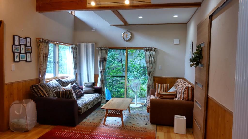 a living room with two couches and a table at Kudo's Lodge in Hakuba