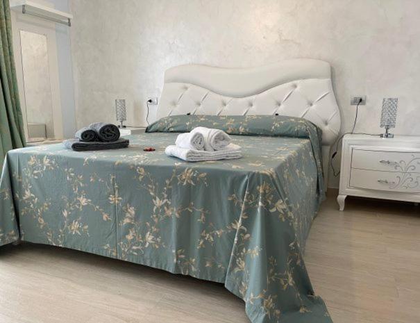 een slaapkamer met een bed met een groene en witte sprei bij Albamaris Guest House in Botricello