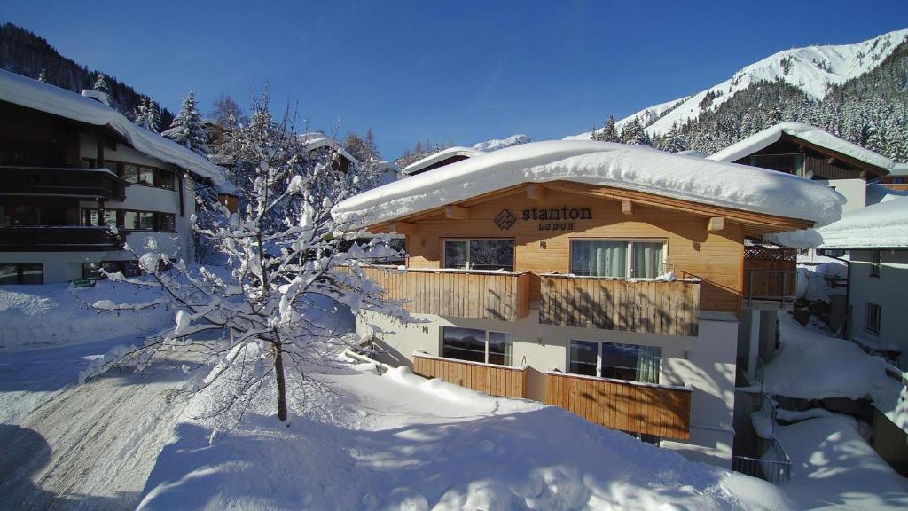 un bâtiment recouvert de neige avec un arbre devant lui dans l'établissement STANTON Lodge, à Sankt Anton am Arlberg