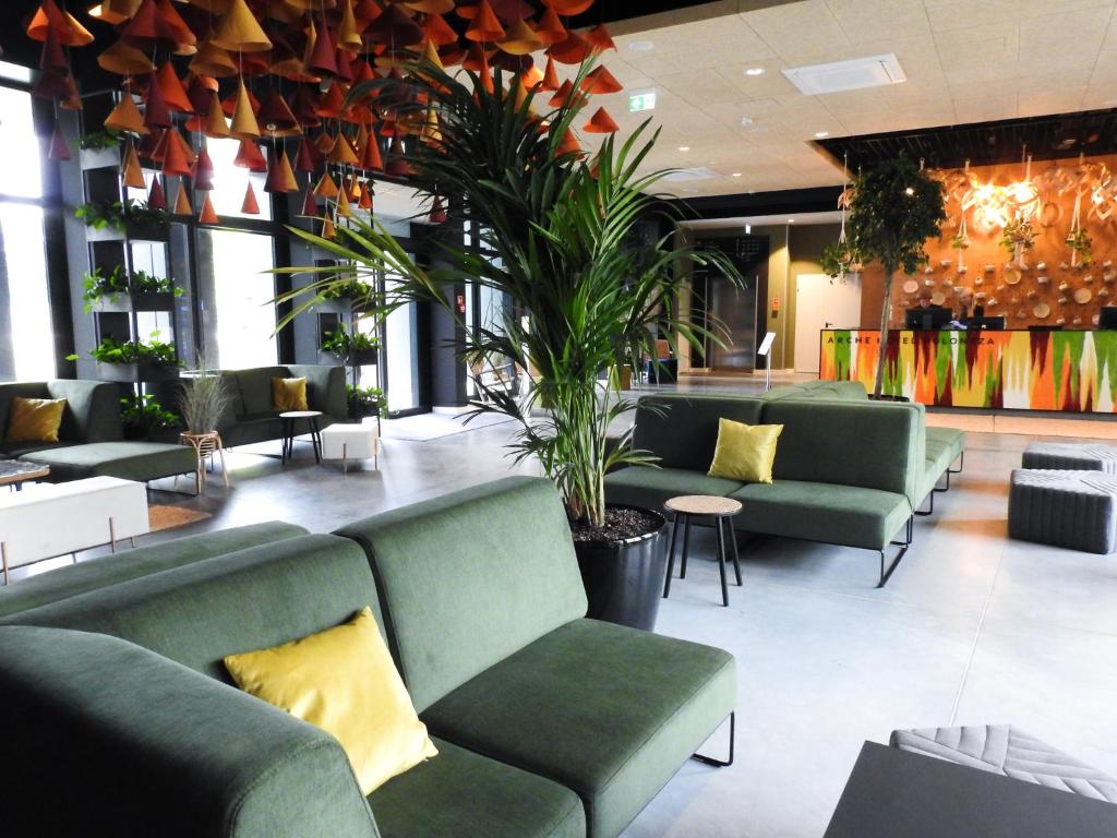 eine Lobby mit grünen Sofas und Pflanzen in der Unterkunft Arche Hotel Poloneza in Warschau