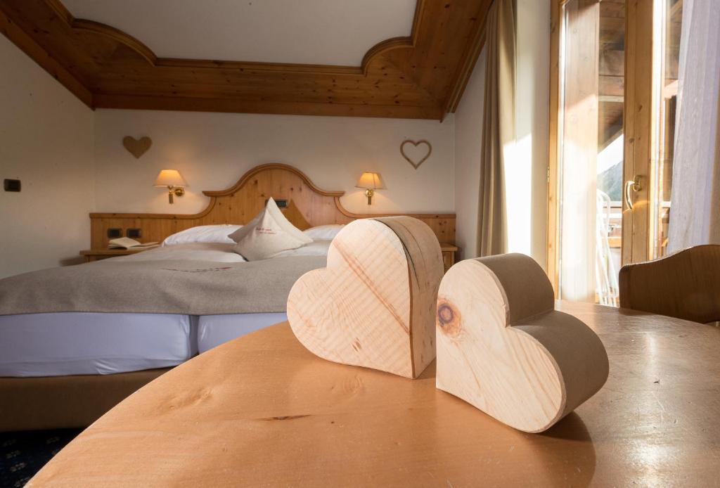 two wooden hearts sitting on a table in a bedroom at Hotel Galli in Livigno