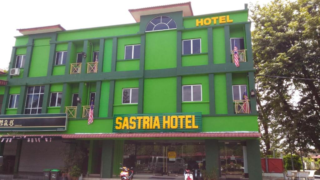 a green hotel with a sign in front of it at Sastria Hotel Sungai Petani in Sungai Petani