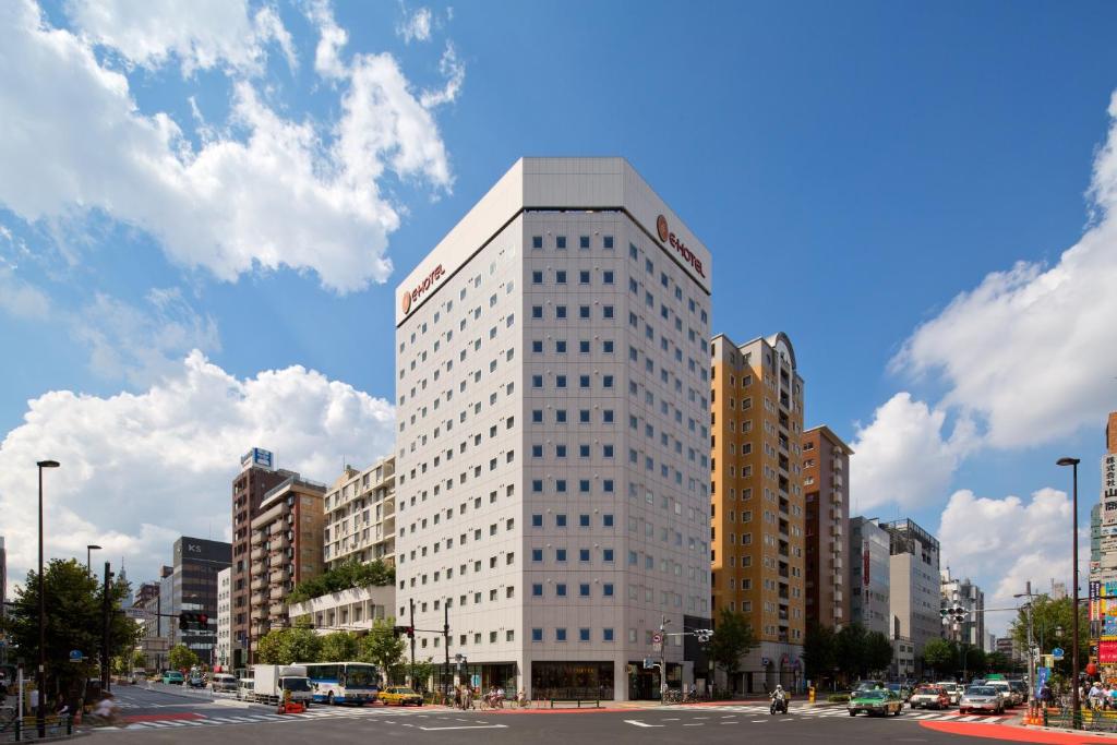 un edificio alto y blanco en medio de una ciudad en E Hotel Higashi Shinjuku, en Tokio