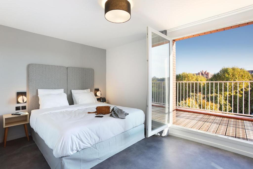 Un dormitorio con una cama y una ventana grande. en Appart Hotel Odalys City Toulouse Centre Compans Caffarelli, en Toulouse