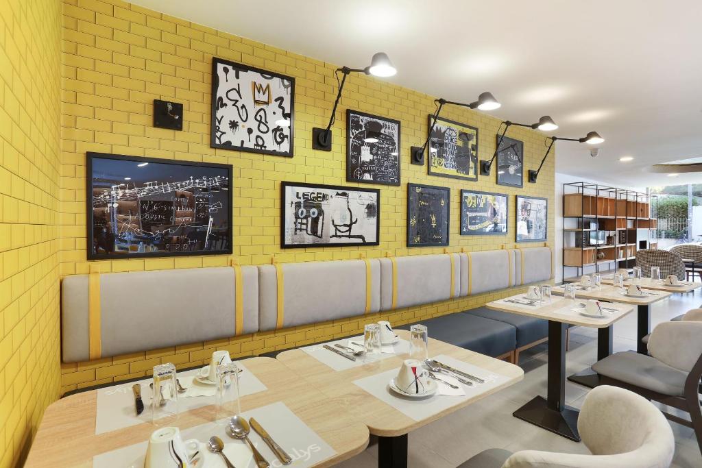 un restaurant avec des tables et des chaises et un mur jaune dans l&#39;établissement Odalys City Toulouse Centre Compans Caffarelli, à Toulouse