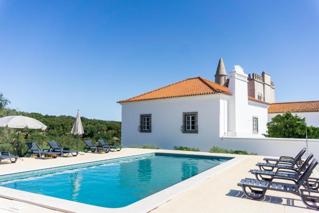 a villa with a swimming pool in front of a house at Torre da Giesteira in São Brissos