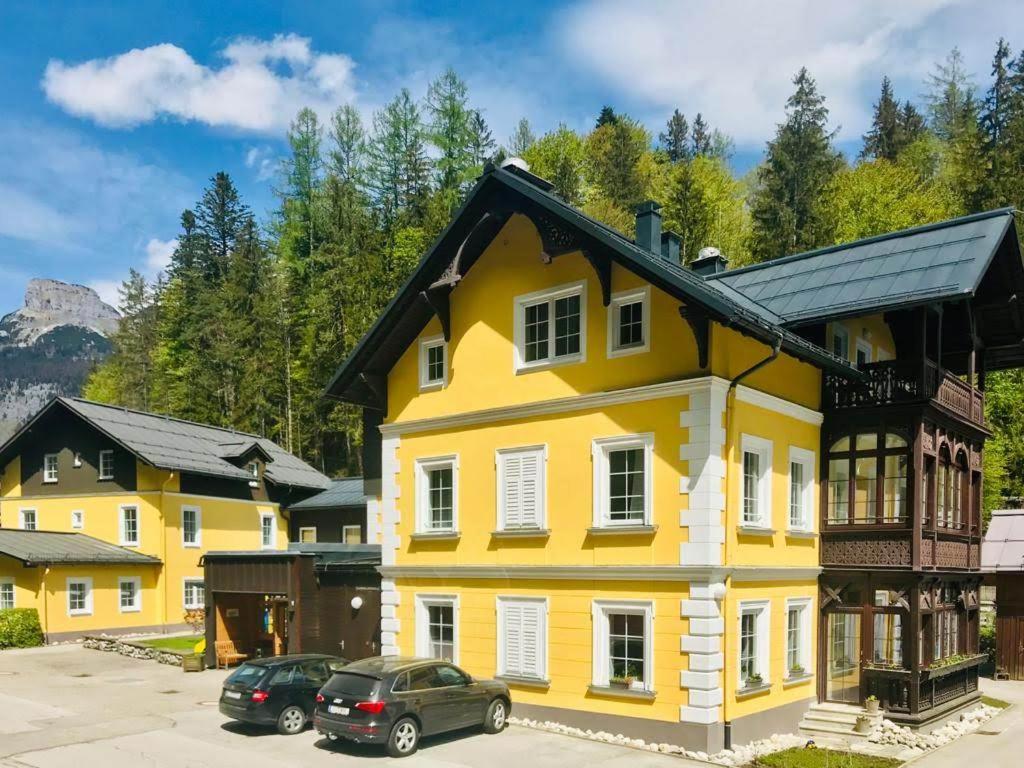 een geel huis met een zwart dak bij Villa Styria in Bad Aussee