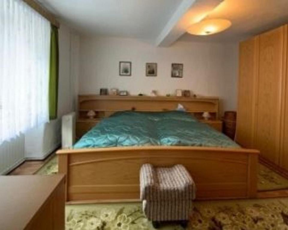 um quarto com uma cama de madeira e uma cadeira em Stadthaus Laucha em Laucha