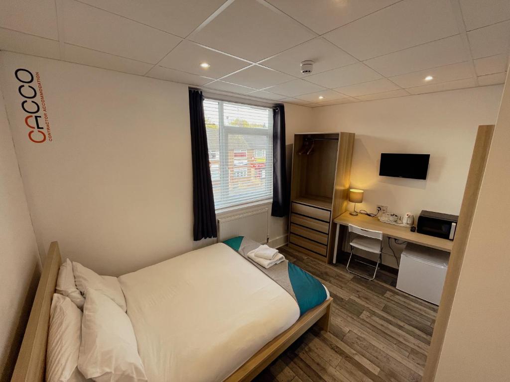 a hotel room with a bed and a desk in it at CACCO - Contractor Accommodation in Corby