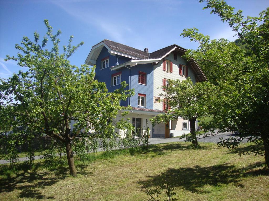 una casa azul y blanca con árboles delante en Hirschfarm, Goldau, en Goldau