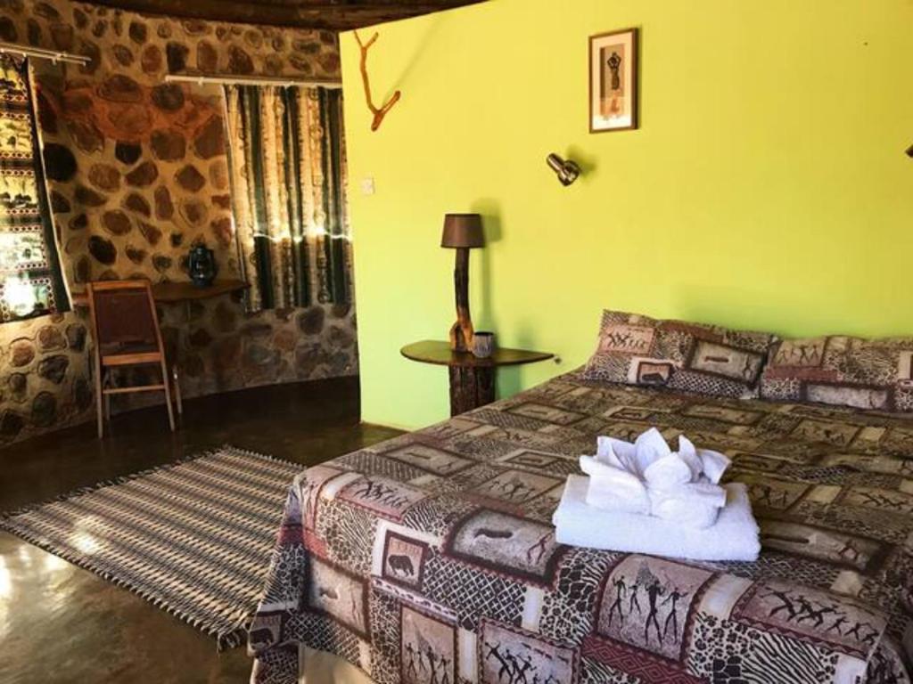 a bedroom with a bed with towels on it at Charming Bush chalet 2 on this world renowned Eco site 40 minutes from Vic Falls Fully catered stay - 1976 in Victoria Falls