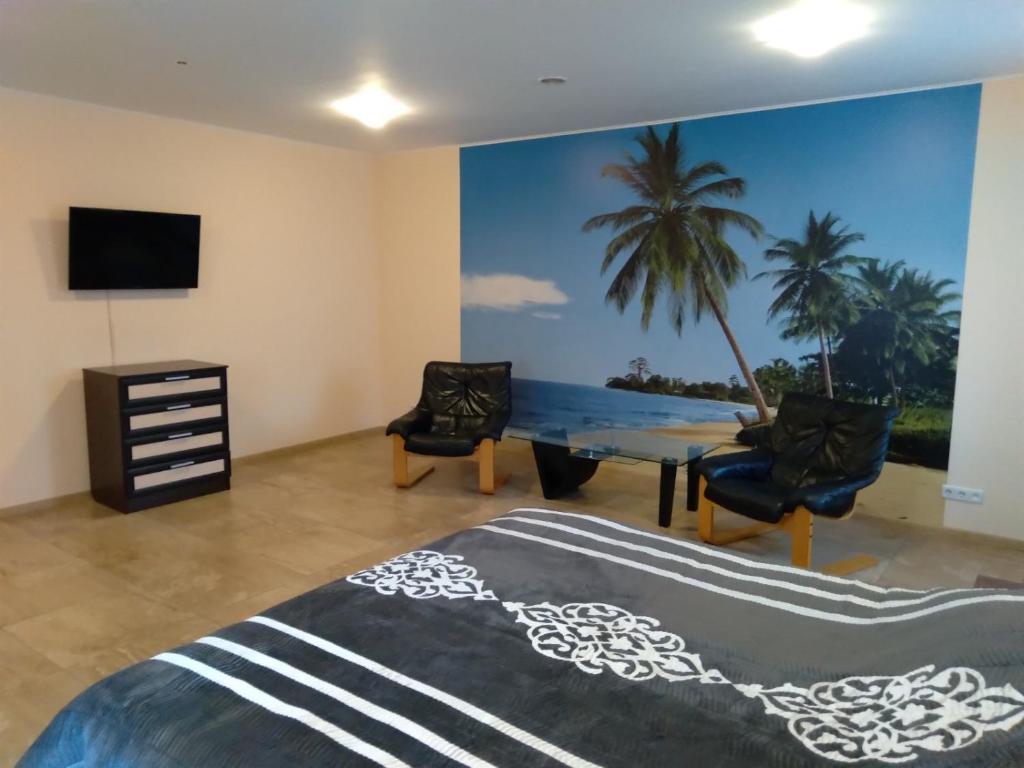 1 dormitorio con mesa, sillas y un mural de palmeras en Апартаменты Анна en Chernihiv