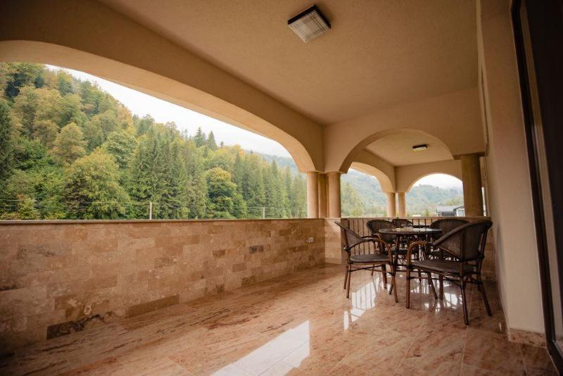 a balcony with a table and chairs and a large window at Casa Măiereană in Anieş
