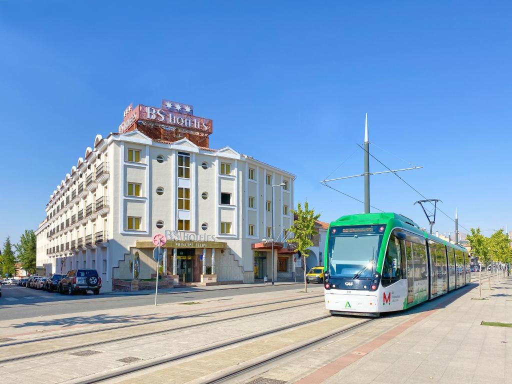 un autobus verde e bianco su una strada con un edificio di BS Principe Felipe ad Albolote