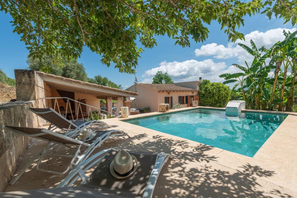 a swimming pool with a chair and a house at Alcudiola in Santa Margalida