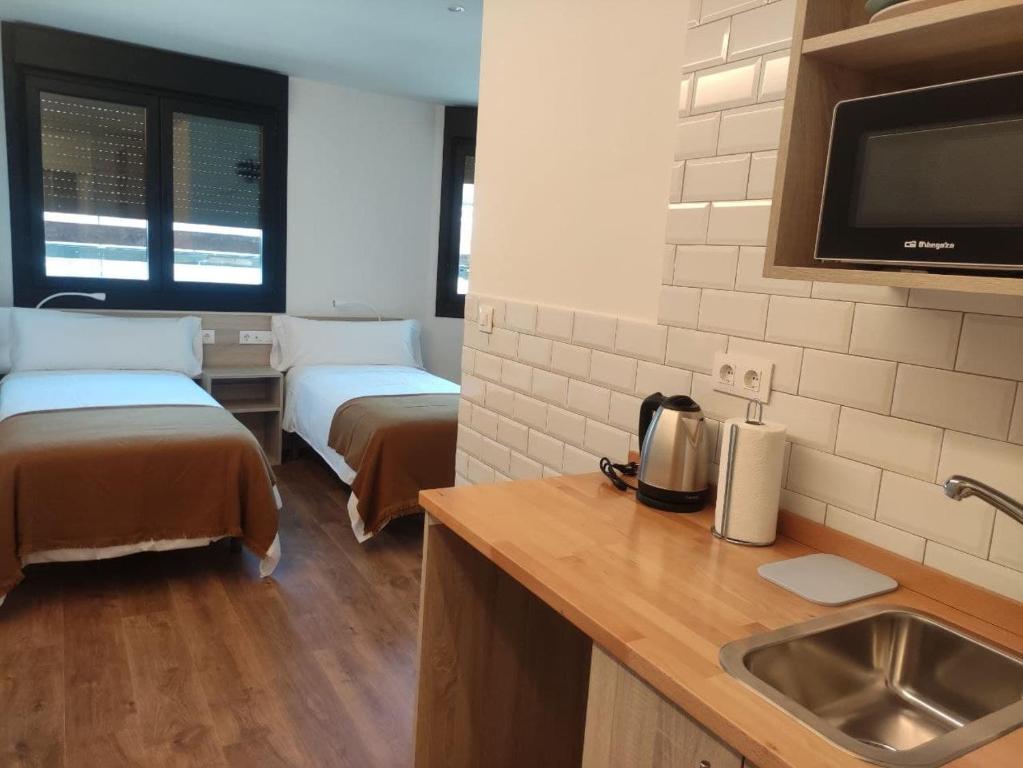cocina con 2 camas y lavabo en una habitación en Alojamientos Central, en Porriño