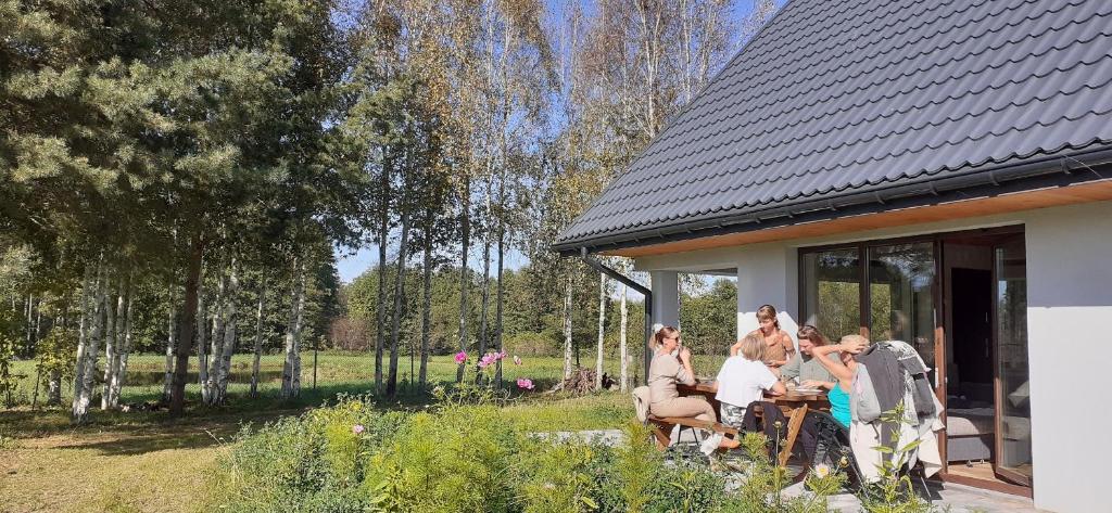 a group of people sitting at a table outside of a house at zajęcza chata in Dolistowo