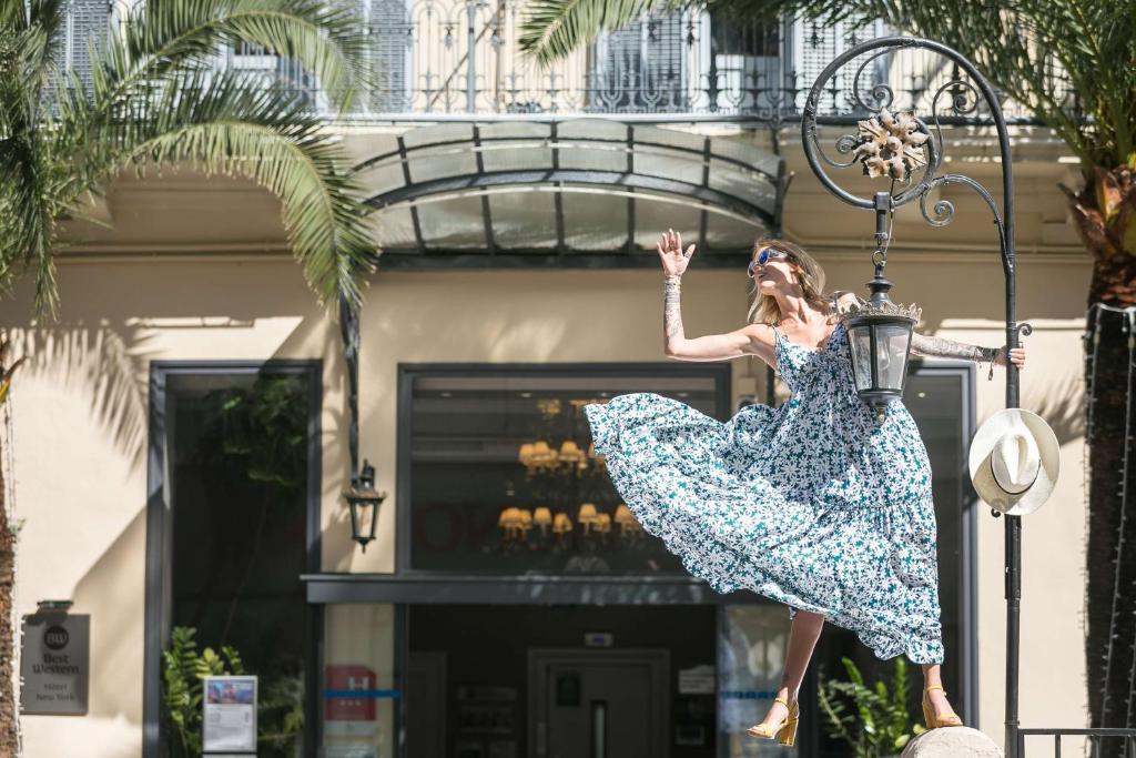 a woman in a dress jumping on a street light at Best Western Hotel Lakmi Nice in Nice