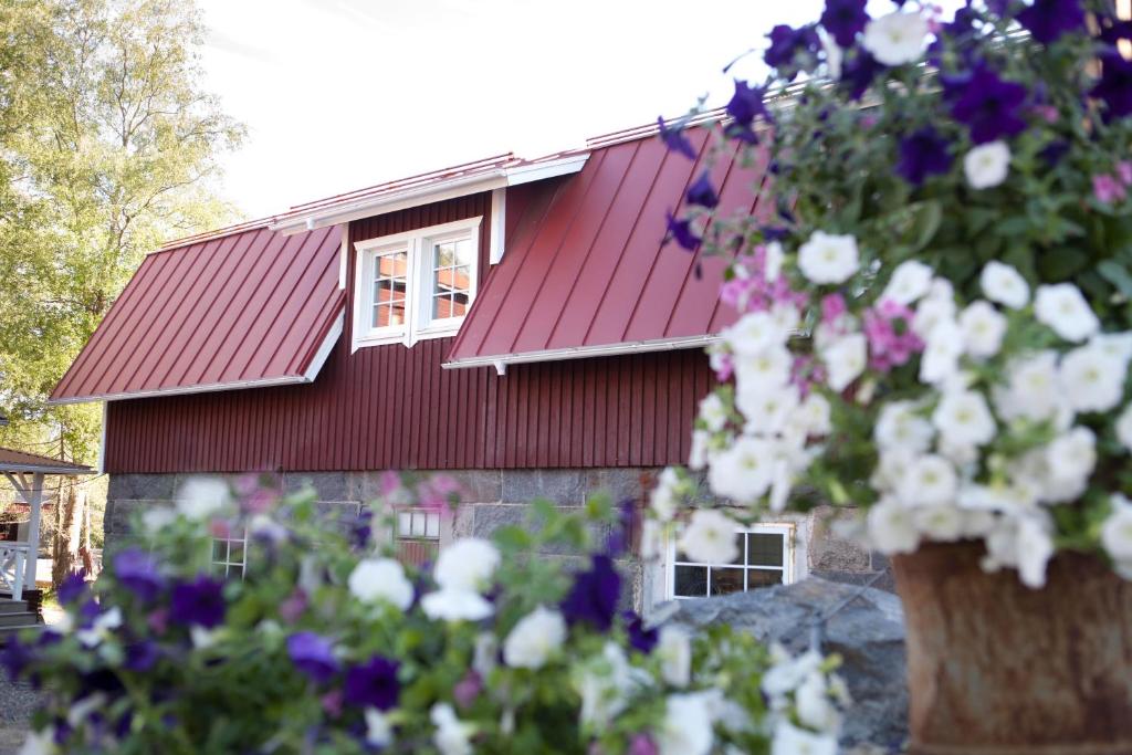 a red roofed house with flowers in front of it at Maatilamatkailu Ali-Ketola in Kokemäki