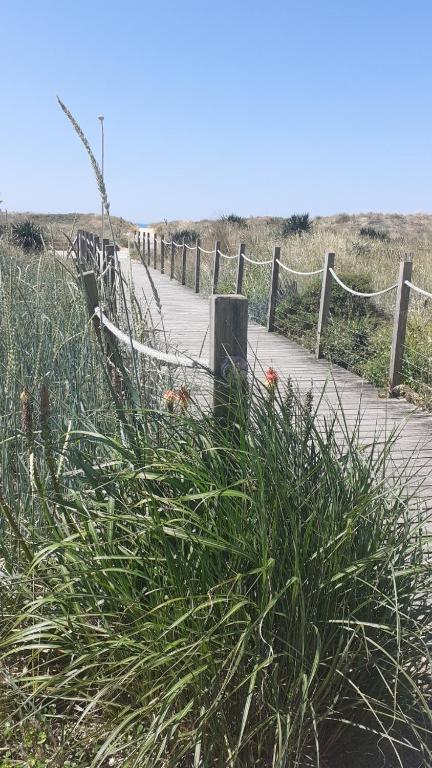 un chemin en bois menant à une plage avec une clôture dans l'établissement Studio - Marina 4 - 17 allée des Pinons - 3-2, à Saint-Jean-de-Monts