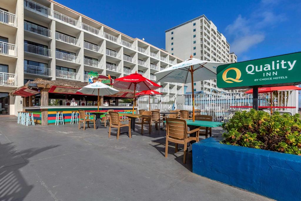 um pátio com mesas e guarda-sóis em frente a um edifício em Quality Inn Boardwalk em Ocean City