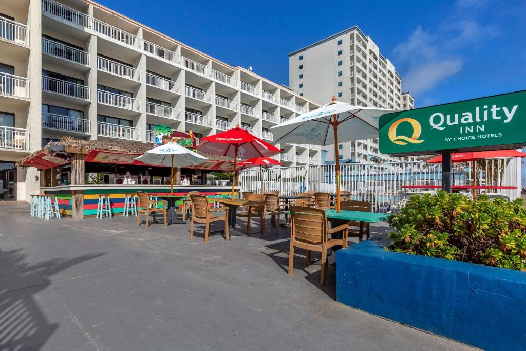 a patio with tables and umbrellas in front of a building at Quality Inn Boardwalk in Ocean City