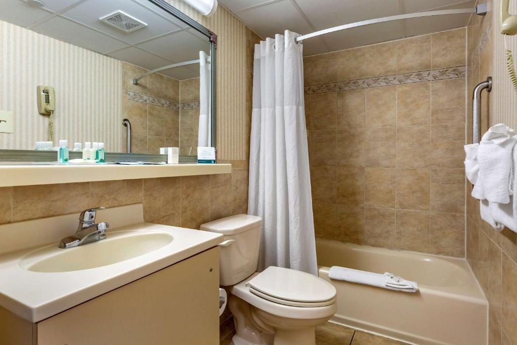 a bathroom with a toilet and a sink and a shower at Quality Inn Boardwalk in Ocean City