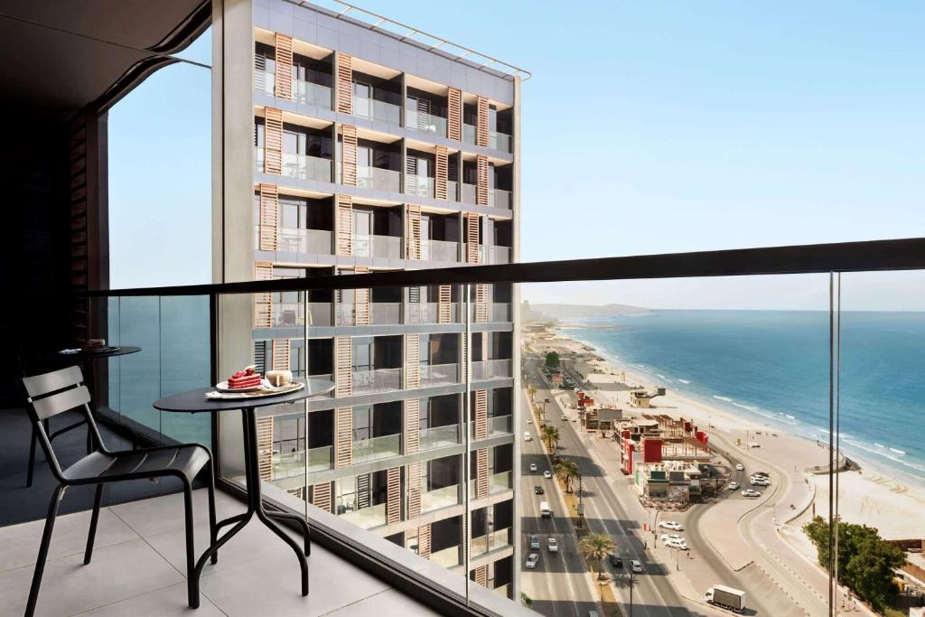 a balcony with a table and a view of the ocean at Wyndham Garden Ajman Corniche in Ajman 