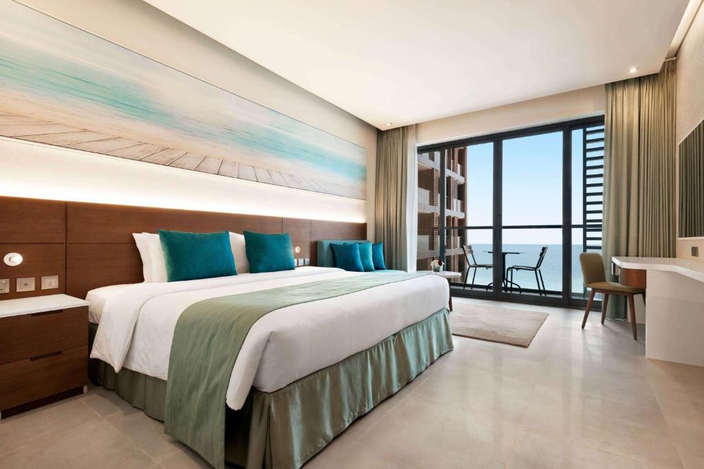 a bedroom with a large bed with a view of the ocean at Wyndham Garden Ajman Corniche in Ajman 