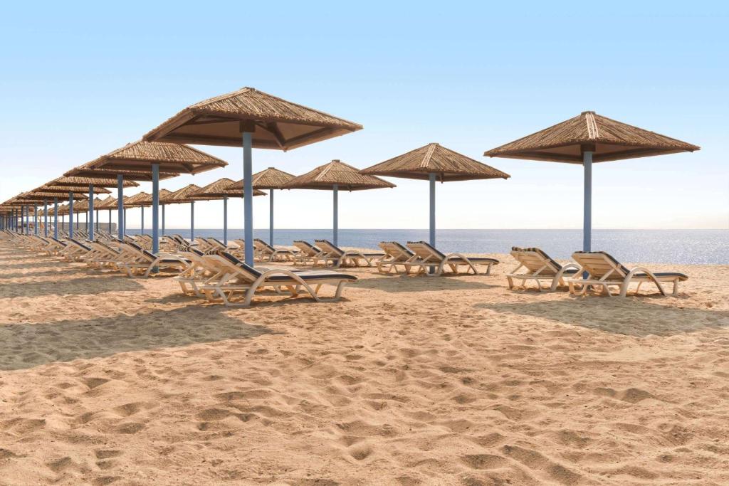 a row of chairs and umbrellas on a beach at Wyndham Garden Ajman Corniche in Ajman 