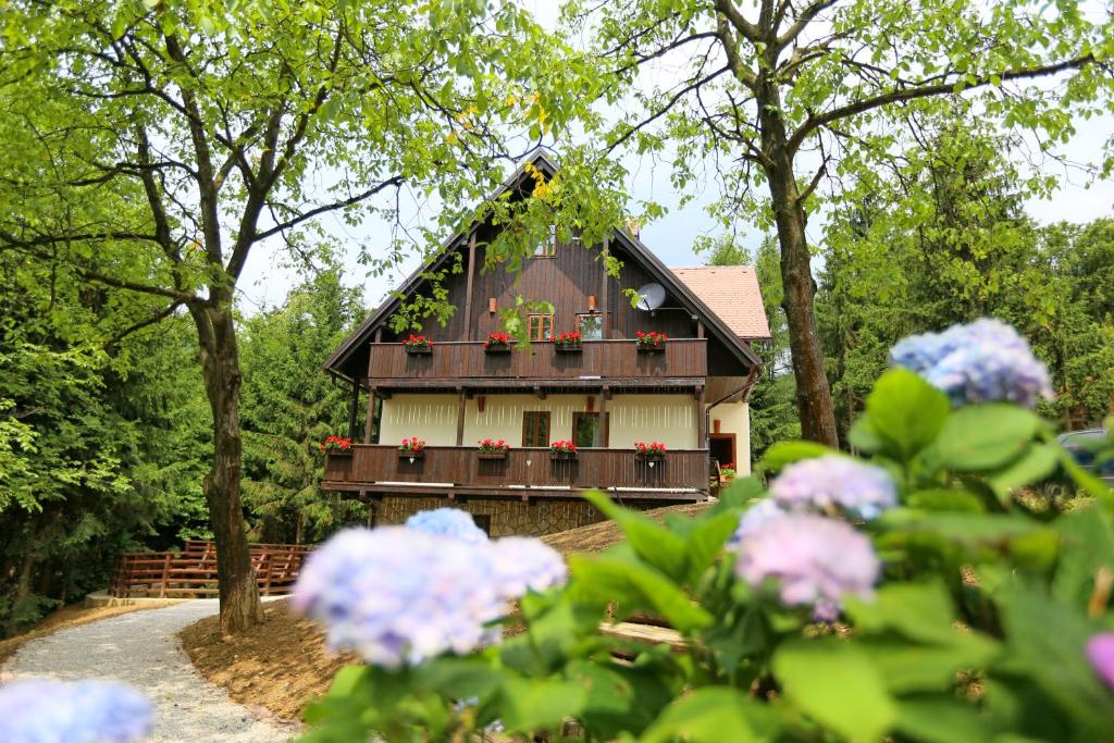 a house with a balcony with flowers in front of it at Pomona Relaxing Nature Guest House in Rogaška Slatina