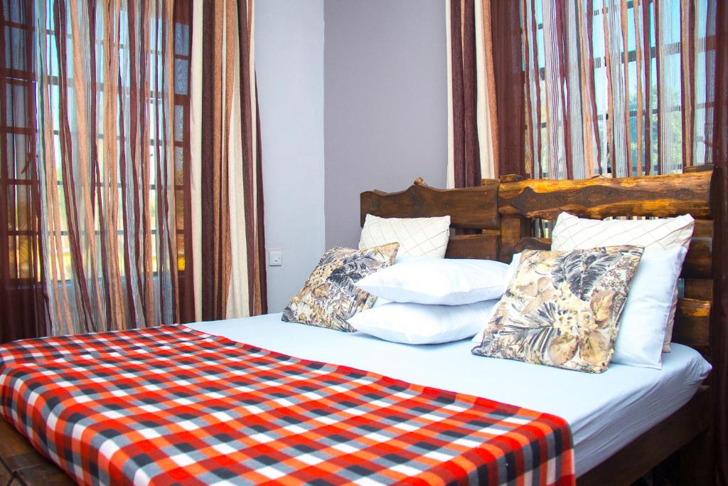Cama con manta y almohadas a cuadros en MINA CHAI HOUSE BNB, en Arusha