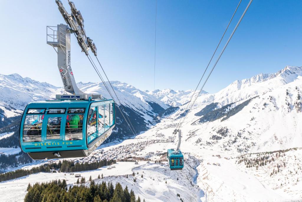 a gondola flying over a snow covered mountain at Catrina Lodge in Disentis